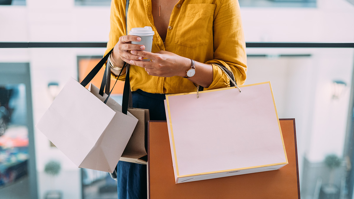 Woman holding a coffee and shopping bags