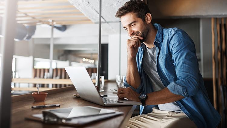 Employee sitting, looking at laptop