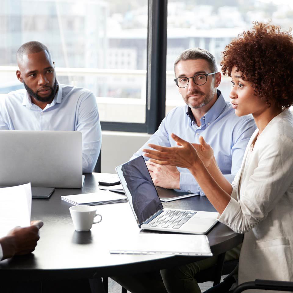 three people discussing information on their laptops